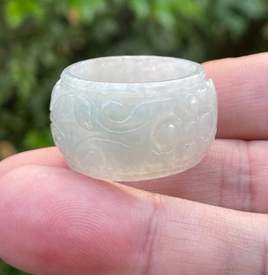 Close-up of continuous hand-carved swirling cloud design on an icy translucent milky white and imperial green Burmese jade ring