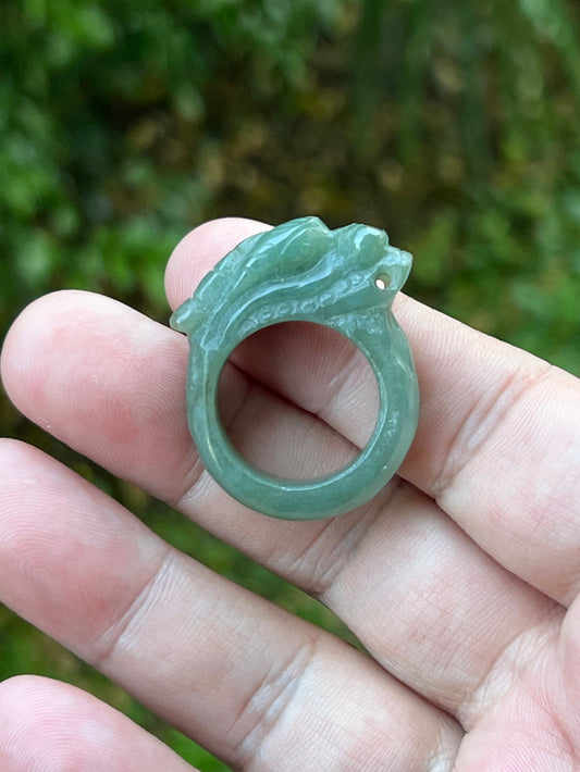 Close-up of dimensional and expressive dragon carving on a semi-translucent apple green Burmese jade ring