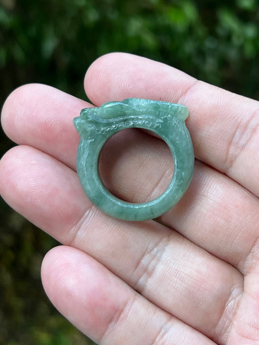 Close-up of defined hand-carved dragon detailing and flowing lines on semi-translucent icy soft green Burmese jade ring