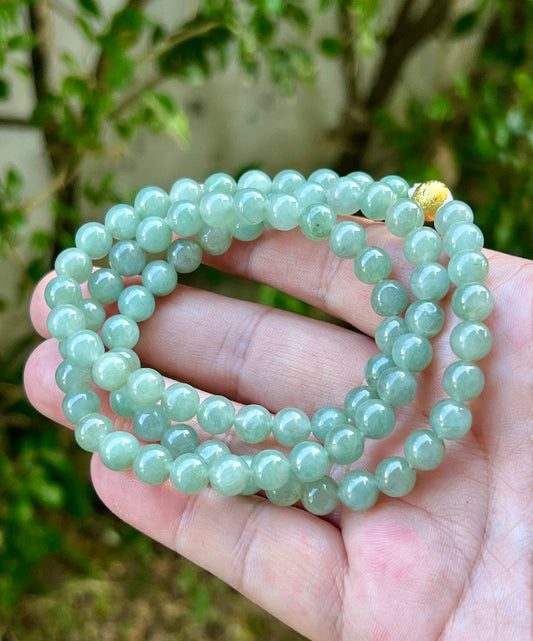 Woman wearing a 23-inch elegant natural Grade A jade bead necklace with a gold-tone twist clasp