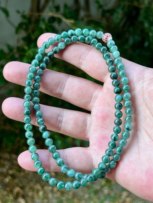 Woman wearing a 22-inch elegant natural Grade A jade bead necklace with a red-tone twist clasp