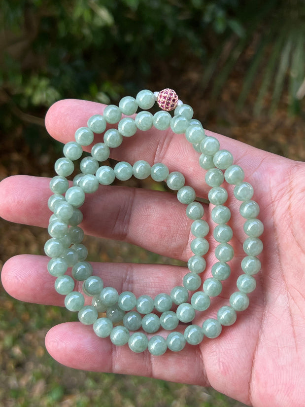 Woman wearing a 23-inch elegant natural Grade A jade bead necklace with a red-tone twist clasp