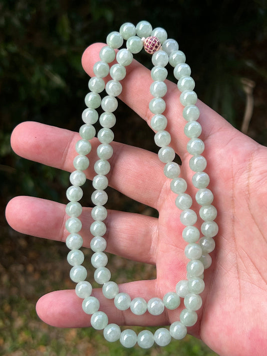 Woman wearing a 22-inch elegant natural Grade A jade bead necklace with a red-tone twist clasp