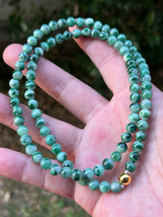 Woman wearing a 22-inch elegant natural Grade A jade bead necklace with a gold-tone twist clasp