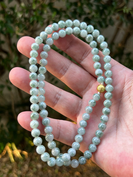 Woman wearing a 23-inch elegant natural Grade A jade bead necklace with a gold-tone twist clasp