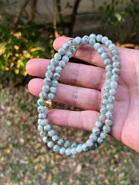 Woman wearing a 23-inch elegant natural Grade A jade bead necklace with a gold-tone twist clasp