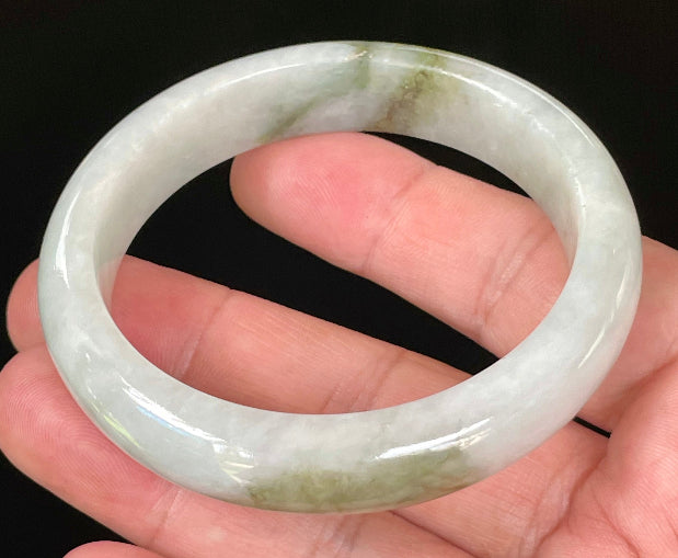 Close-up of fine crystalline texture and beautiful moss green swirls on icy apple green and white jadeite bangle