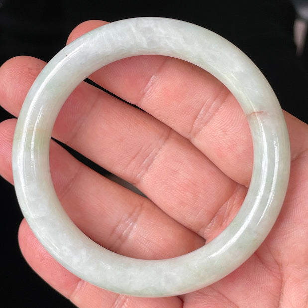Close-up of fine crystalline texture and a natural orange line on icy milky white and apple green jadeite bangle