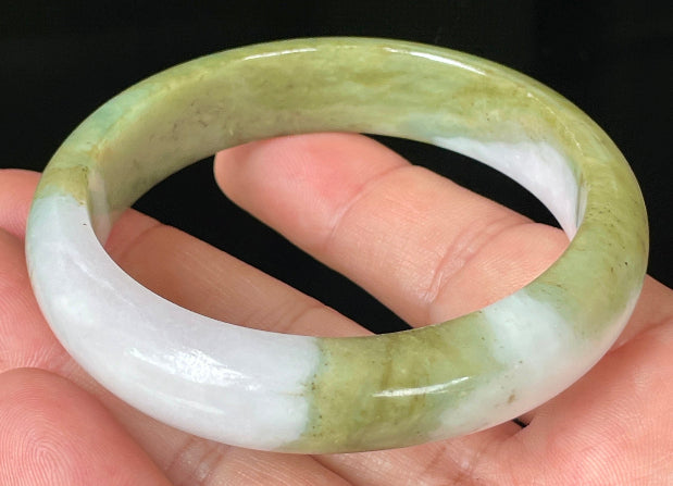 Close-up of fine crystalline texture and rich forest green tones on icy apple green jadeite bangle