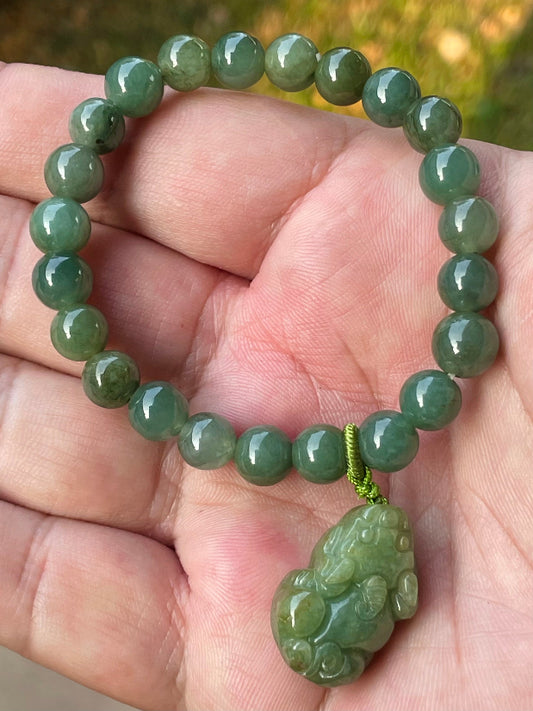 7mm natural Type A Burmese jade beads showing gentle translucency, deep apple green hues, and a hand-carved Pixiu pendant on the wrist