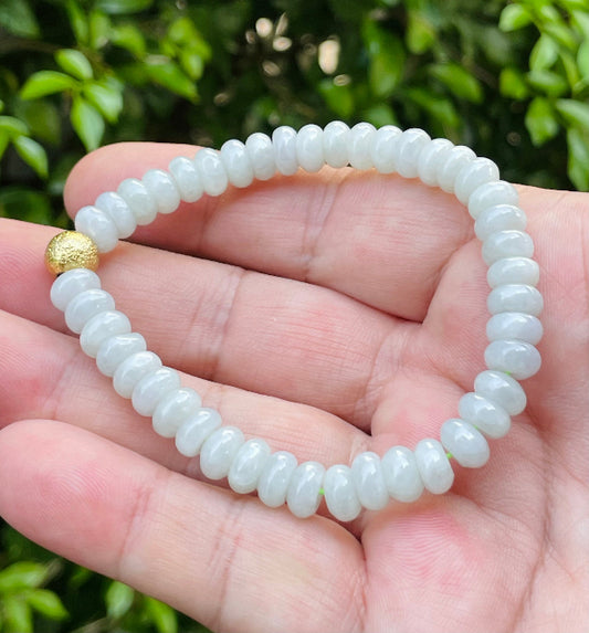 7.7mm natural Type A Burmese jade beads showing gentle translucency, icy green colors, and a matte gold accent on the wrist