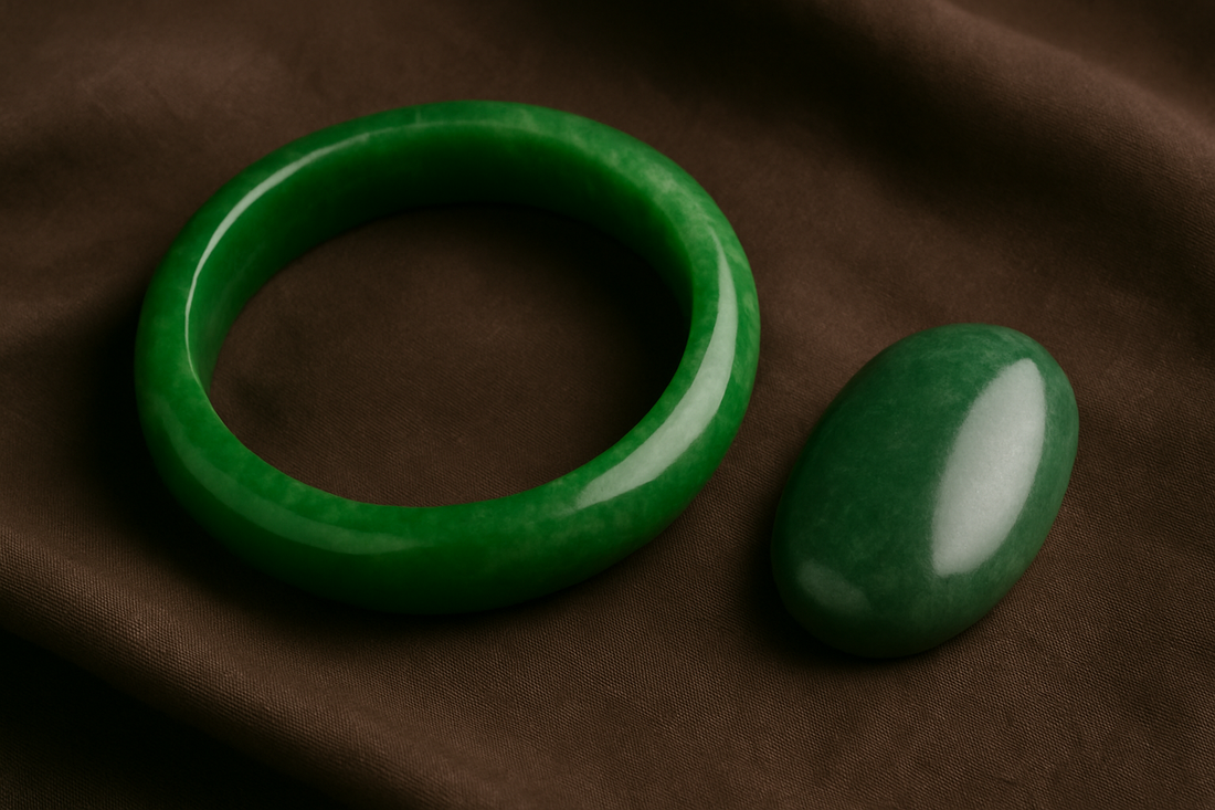Polished imperial green jadeite cabochon and hand-carved jade bangle displayed on dark silk fabric under soft natural light