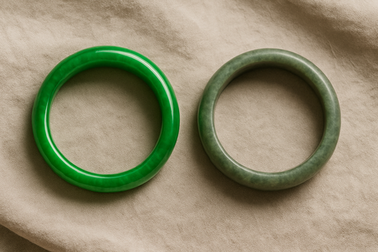 Two jade bangles resting side by side on soft beige fabric—one vibrant and glossy, the other matte and muted—illustrating how jade can subtly change color or luster over time.