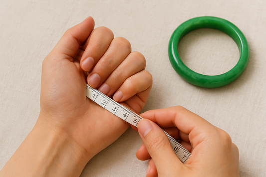 A realistic photo of a hand with fingers tucked, being measured around the knuckles with a white tape, while a green jade bangle rests nearby on a soft beige fabric—illustrating how to measure for the right jade bangle size.