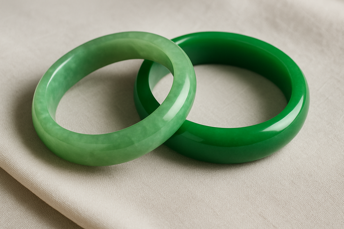 Two jade bangles on a soft off-white fabric—one with subtle, natural color variations and translucency, the other a richer, more opaque green—highlighting the visual difference between natural and treated jade.