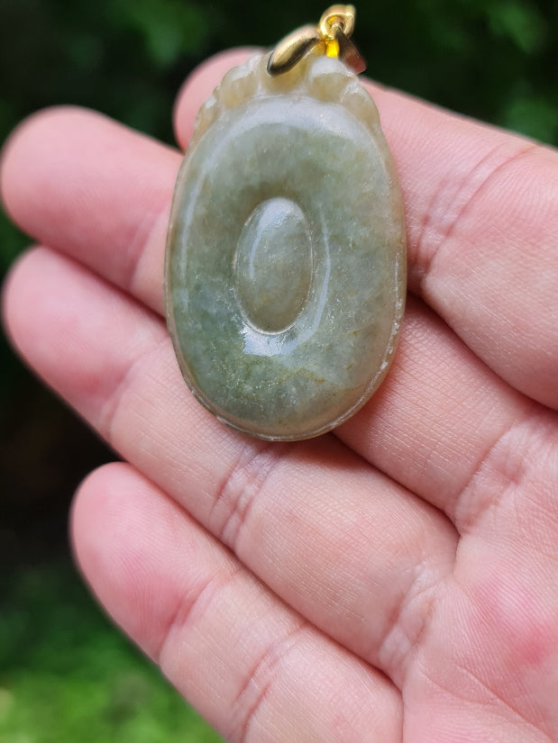 Untreated Type A Burmese jade pendant showing a smooth polished finish with beautiful imperial green and warm honey tones