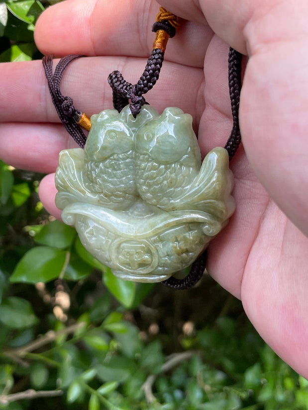 Glossy luster and medium texture of the authentic Myanmar jade pendant JP038 showcasing a carved twin fish Feng Shui design for wealth and abundance
