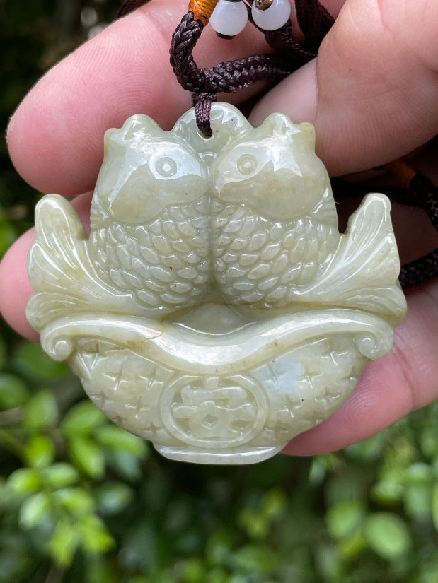 Glossy luster and medium texture of the authentic Myanmar jade pendant JP038 showcasing a carved twin fish Feng Shui design for wealth and abundance