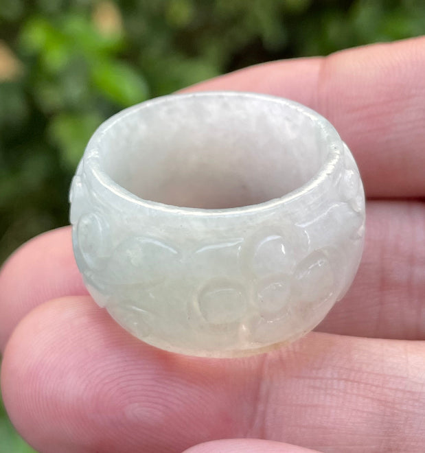 Close-up of continuous hand-carved swirling cloud design on an icy translucent milky white and imperial green Burmese jade ring