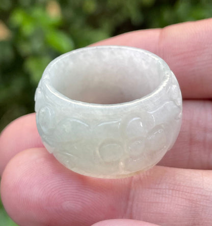 Close-up of continuous hand-carved swirling cloud design on an icy translucent milky white and imperial green Burmese jade ring