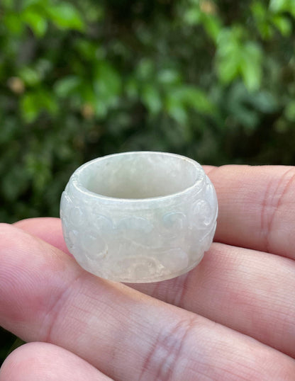 Close-up of continuous hand-carved swirling cloud design on an icy translucent milky white and imperial green Burmese jade ring