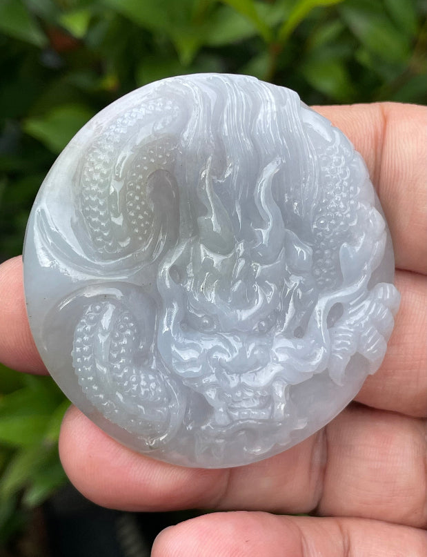 Untreated Type A Burmese jade pendant showing a smooth polished finish with an intricate Dragon carving and flame-like tail