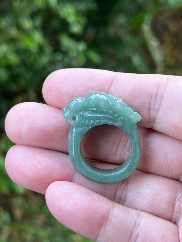 Close-up of dimensional and expressive dragon carving on a semi-translucent apple green Burmese jade ring