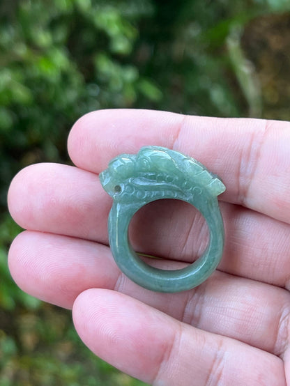 Close-up of dimensional and expressive dragon carving on a semi-translucent apple green Burmese jade ring