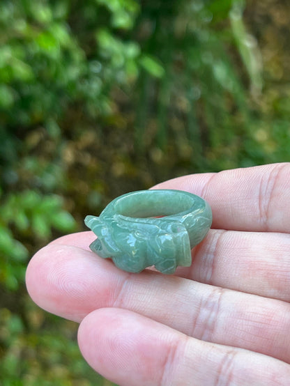 Close-up of dimensional and expressive dragon carving on a semi-translucent apple green Burmese jade ring