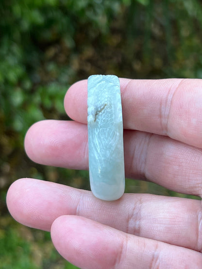 Close-up of defined dragon head and fine textural detailing on a semi-translucent icy bluish-white Burmese jade ring
