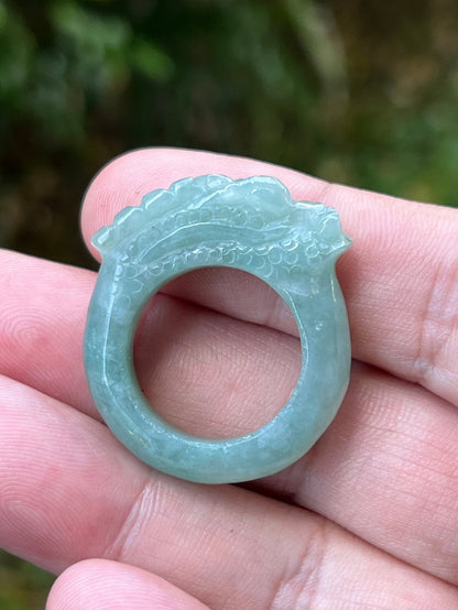 Close-up of refined hand-carved dragon detailing and smooth flowing lines on a semi-translucent icy green Burmese jade ring