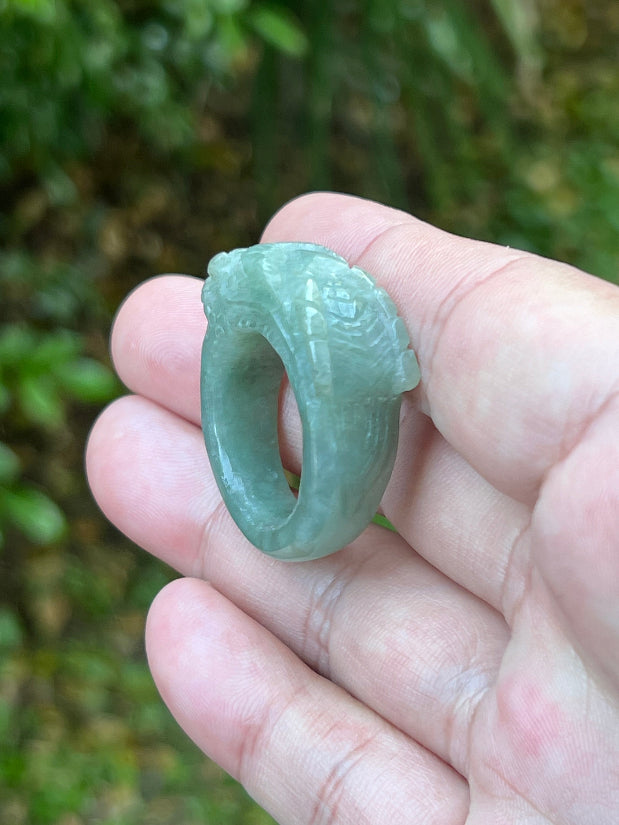Close-up of layered carving and well-defined dragon body on a semi-translucent icy green Burmese jade ring