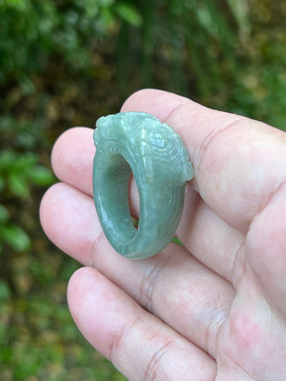 Close-up of layered carving and well-defined dragon body on a semi-translucent icy green Burmese jade ring