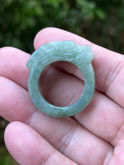 Close-up of layered carving and well-defined dragon body on a semi-translucent icy green Burmese jade ring