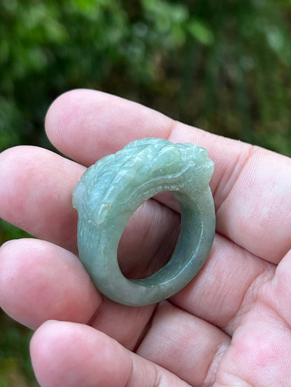 Close-up of layered carving and well-defined dragon body on a semi-translucent icy green Burmese jade ring