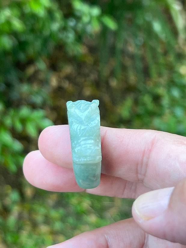 Close-up of layered carving and well-defined dragon body on a semi-translucent icy green Burmese jade ring