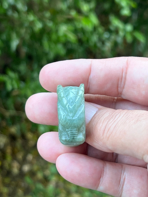 Close-up of pronounced facial definition and raised dragon carving on a semi-translucent icy green Burmese jade ring
