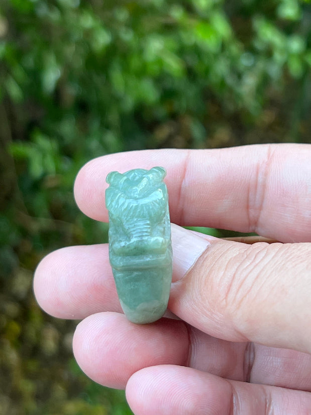 Close-up of pronounced facial definition and raised dragon carving on a semi-translucent icy green Burmese jade ring