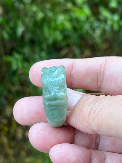 Close-up of pronounced facial definition and raised dragon carving on a semi-translucent icy green Burmese jade ring