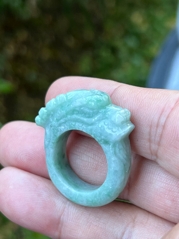 Close-up of intricate hand-carved dragon detailing on a semi-translucent icy green Burmese jade ring
