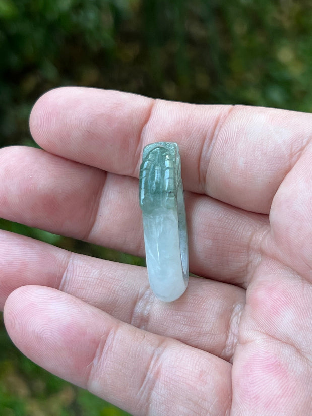 Close-up of layered scale work and detailed hand-carved dragon on a semi-translucent icy white and green Burmese jade ring