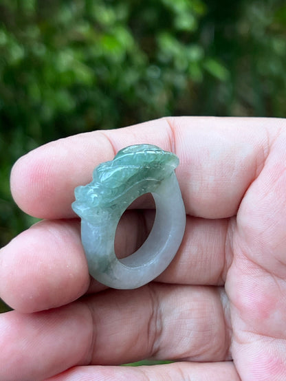 Close-up of layered scale work and detailed hand-carved dragon on a semi-translucent icy white and green Burmese jade ring