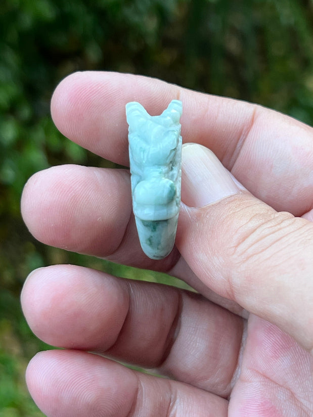 Close-up of rounded fluid carving and bead-like detailing on an icy white and moss green Burmese jade ring