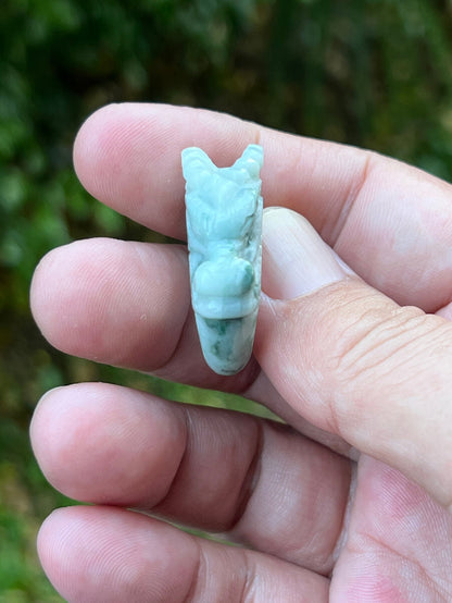 Close-up of rounded fluid carving and bead-like detailing on an icy white and moss green Burmese jade ring