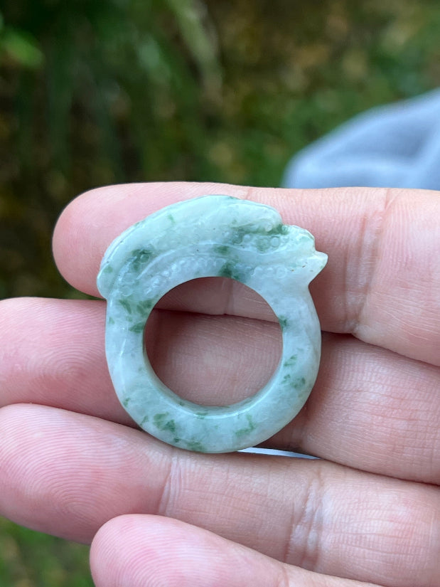 Close-up of flowing lines and bead-like scale detailing on icy white and moss green Burmese jade ring