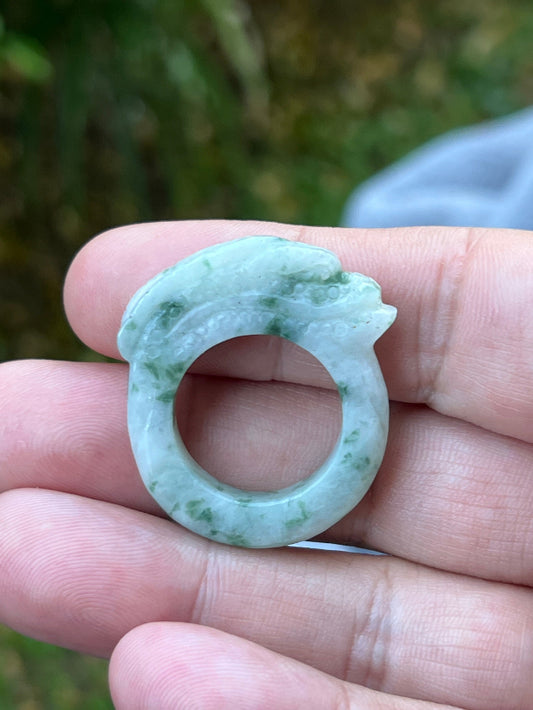Close-up of flowing lines and bead-like scale detailing on icy white and moss green Burmese jade ring