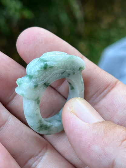 Close-up of flowing lines and bead-like scale detailing on icy white and moss green Burmese jade ring