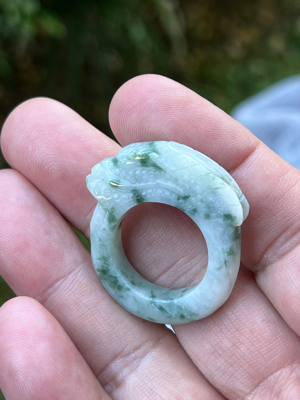 Close-up of flowing lines and bead-like scale detailing on icy white and moss green Burmese jade ring