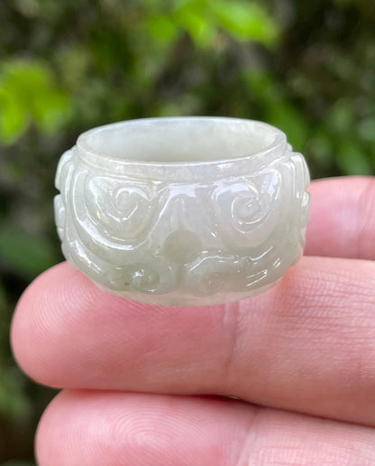 Close-up of intricately hand-carved floral petals and organic curves on an icy apple green Burmese jade ring