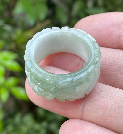 Close-up of intricate hand-carved floral petals and organic curves on an icy apple green Burmese jade ring